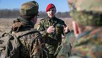 Der Truppenpsychologe spricht zu einer Gruppe Soldaten im Gelände.