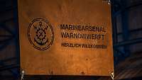 Auf einer Stahlplatte steht der Schriftzug: Marinearsenal Warnowwerft, herzlich willkommen.