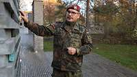 Ein Soldat im Feldanzug hält die Hand an eine der Stelen im Wald der Erinnerung