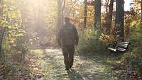 Soldat im Feldanzug läuft in Gegensonne durch einen herbstlichen Wald