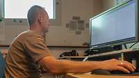 Ein Soldat sitzt in einem Büro vor einem PC
