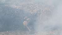 Ein Soldat hockt im Nebel auf dem Boden und bringt ein Sprengrohr an einer Sperre an