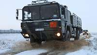 Ein Bundeswehrtanklastkraftwagen fährt durch eine aufspritzende Pfütze