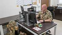 Ein Soldat sitzt an einem Computerarbeitsplatz.