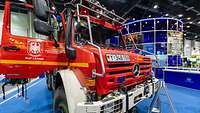 Ein Feuerwehr-Unimog mit geöffneter Tür vor einem Messestand