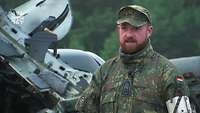 Ein Soldat steht vor teilweise erkennbarem Bundeswehrgerät