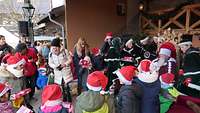 Kinder mit Weihnachtsmützen und Geschenken in der Hand