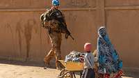 Ein Soldat läuft zwei Kindern mit einer Schubkarre entgegen