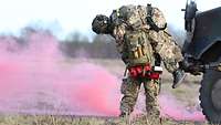 Ein Soldat trägt einen anderen auf seinen Schultern, vor ihm steigt rosafarbener Nebel auf.