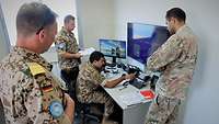 Zwei deutsche und zwei libanesische Soldaten sind in einem kleinen Raum mit Monitoren
