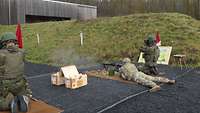 Ein Bundeswehrsoldat beobachtet das Ziel und berichtet dem US-Soldaten am Maschinengewehr über das Trefferbild. 