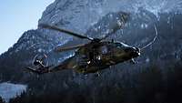 Ein Hubschrauber vom Typ NH-90 fliegt über eine verschneites Gebirge.