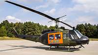 Ein Hubschrauber vom Typ Bell UH-1D mit der Aufschrift SAR steht auf dem Flugfeld