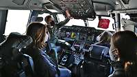 Im Cockpit eines Flugzeugs vom Typ A400M zeigt ein Pilot einigen Mädchen die zahlreichen Knöpfe und Einstellungsmöglichkeiten.