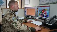 Ein Soldat sitzt vor einem Bildschirmarbeitsplatz und bearbeitet Flyer.