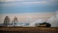 Ein Leopard 2A5 steht auf einem brennenden Feld.