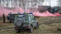 Mehrere Fahrzeuge stehen in einer rosa Nebelwand