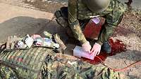 Ein Soldat versorgt eine künstliche Wunde an einem Präparat aus Silikon.