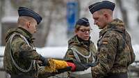 Drei deutsche Soldaten entpacken die deutsche Truppenfahne.