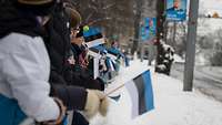 Zuschauer stehen mit Estland-Fahnen hinter einer Absprerrung und schauen auf die Paradestrecke.