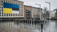 Die Militärkapelle steht auf dem Freiheitsplatz, im Hintergrund an einem Haus die estnische und die ukrainische Flagge.