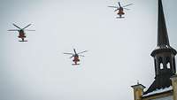 Drei Search and Rescue Hubschrauber überfliegen die Parade an einem Kirchturm vorbei
