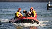 Zivile Rettungskräfte fahren mit einem Schlauchboot Verwundete übers Wasser