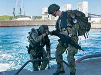 Ein Soldat hilft seinem Kameraden beim Ausstieg aus einem Schnellboot auf die Hafenkante.