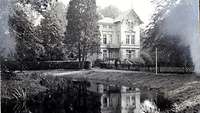 Eine Schwarz-Weiß-Fotografie – vermutlich aus den 1930er Jahren – zeigt den Teich im Vordergrund und die Villa Plaut.