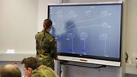 Soldatin schreibt auf einem interaktiven digitalen Whiteboard.