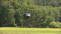 Mehrzweckhubschrauber Bell UH-1 D in der Luft vor einen grünen Wald.