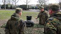 Ein Soldat erklärt zwei anderen Soldaten ein technisches Gerät.