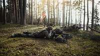 Soldaten liegen im Wald am Boden in Stellung mit ihren Waffen im Anschlag
