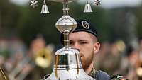 Ein Soldat mit einem metallisch glänzenden glockenähnlichen Instrument