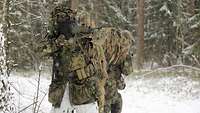Ein Soldat steht im verschneitem Wald mit einer Waffe im Anschlag.