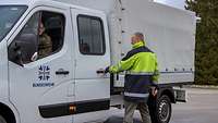 In einen Bundeswehrtransporter steigt ein Mann in Warnkleidung 