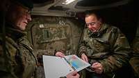 Minister Pistorius sitzt mit einem Soldaten in einem Militärfahrzeug und schaut auf eine Karte