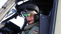 Ein NH-90-Pilot sitzt am Tag im Hubschrauber-Cockpit und blickt in die Kamera.