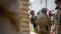 Die Soldaten suchen mit der Trage für den Verwundeten hinter Sandsäcken und einem Bunker Schutz.