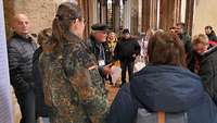 Menschen stehen in einem Kreis zusammen und lauschen einem Tourguide in einer Kirche.