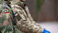 Zwei Soldaten in einer deutschen und ukrainischen Uniform stehen nebeneinander