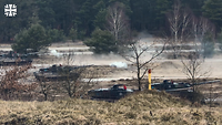 Vier Panzer stehen im Gelände und schießen.
