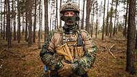 Portraitaufnahme von einem Soldaten der im Wald vermummt ist.