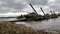 Über einen Fluss ist eine improvisierte Brücke gelegt. Darüber fahren Panzer zum anderen Ufer.