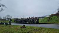 Eine Gruppe von Soldatinnen und Soldaten beim Antreten auf einer Straße im Grünen