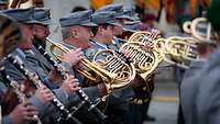 Soldaten stehen in Formation und spielen auf Musikinstrumenten.