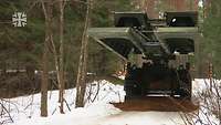 Ein Brückenlegepanzer Biber steht im verschneiten Wald.