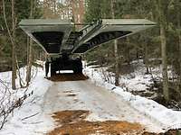 Ein Brückenlegepanzer Biber fährt seine Brücke aus in einem verschneiten Wald