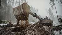 Ein Pionierpanzer Dachs bei Baggerarbeiten in einem verschneiten Wald