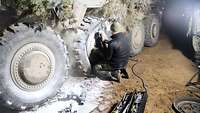 Ein Soldat wechselt einen vom Löschpulver weiß eingestaubten Reifen an einem Gefechtsfahrzeug